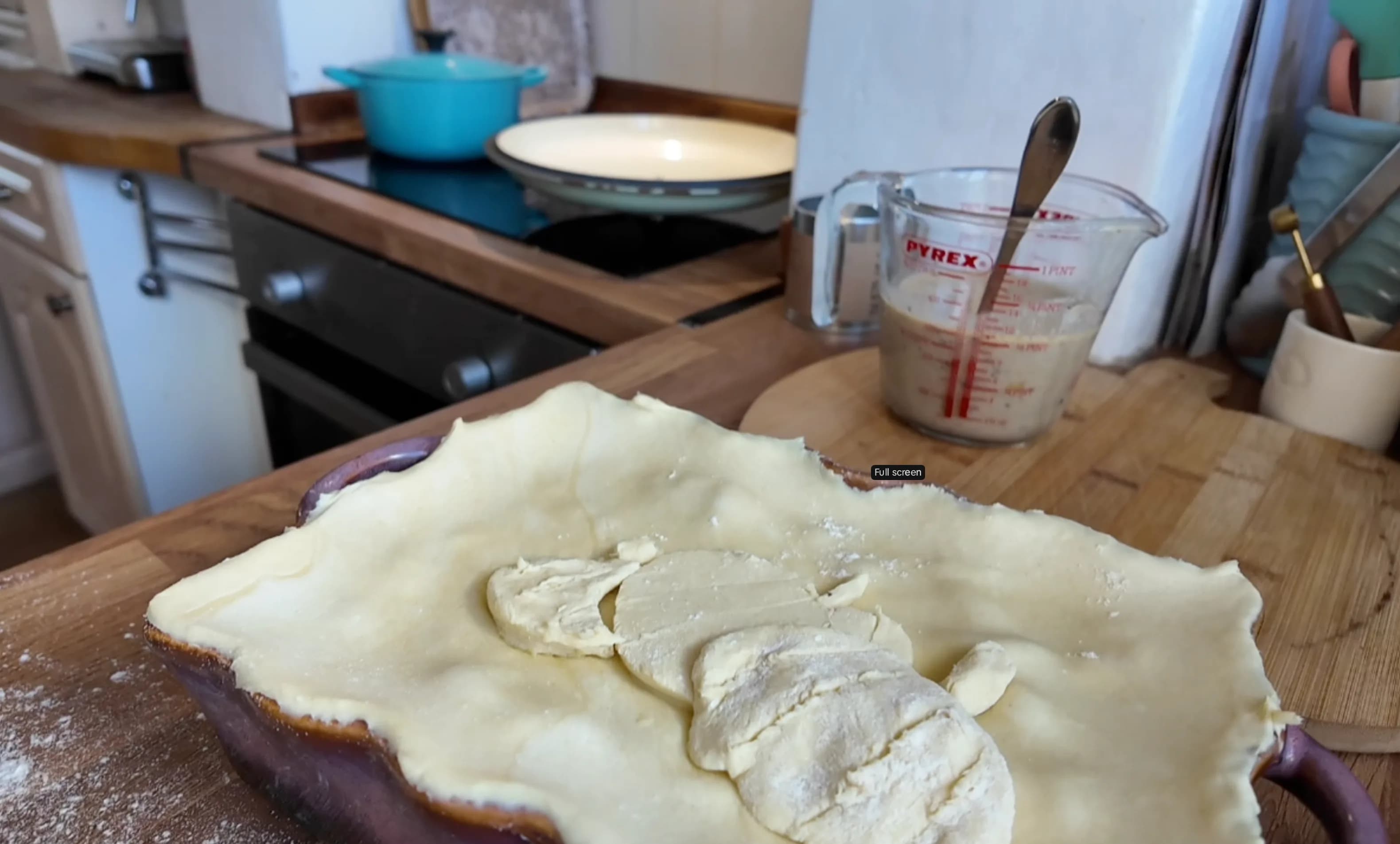 Pie partially covered with puff pastry and a slit in the centre.